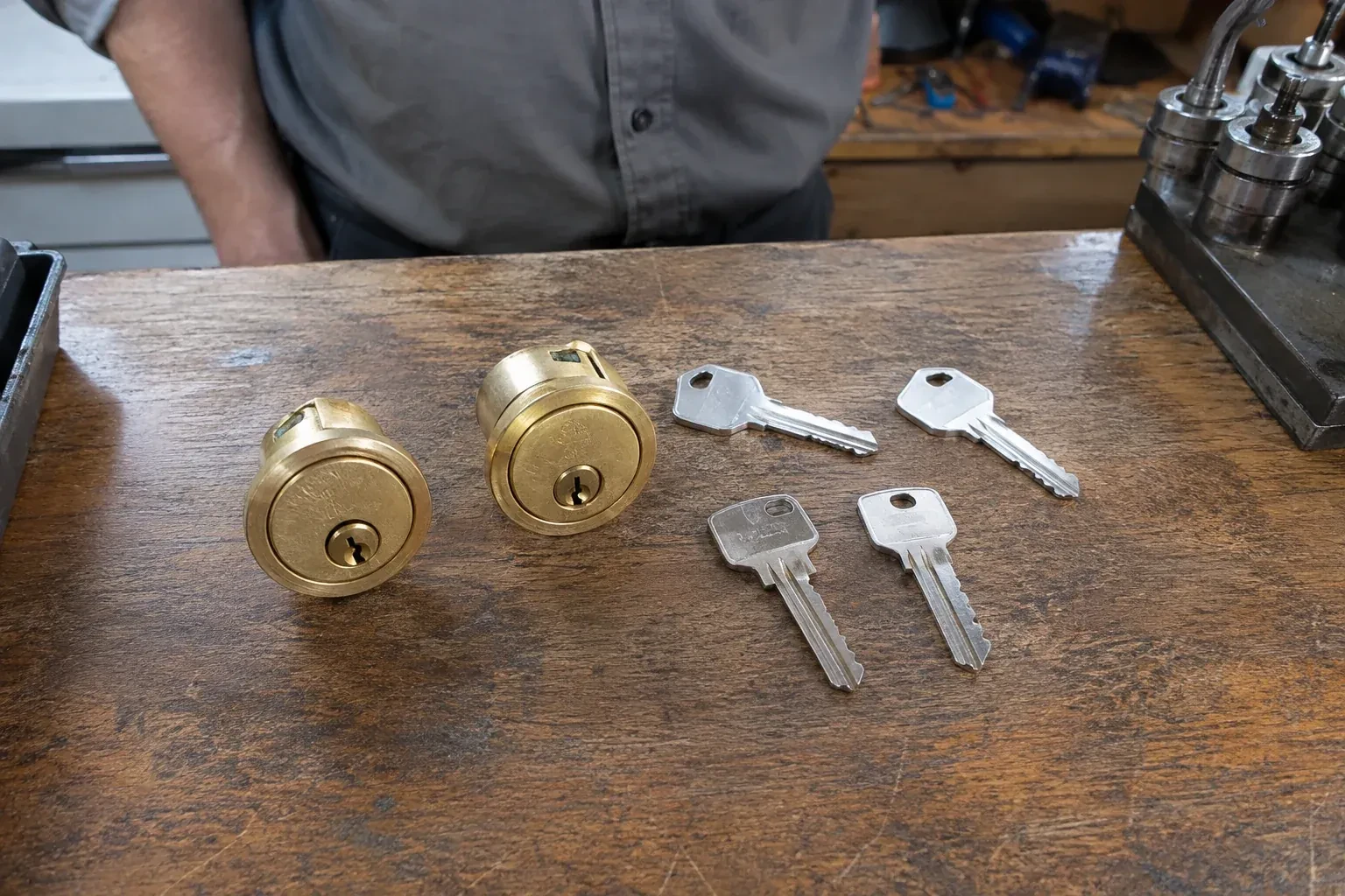Two detached brass lock cylinders and four house keys on a wooden counter. — Lock Rekeying, Brantford